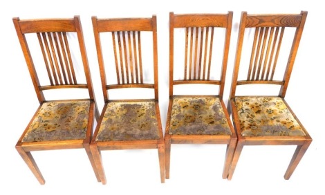 A set of four early 20thC oak dining chairs, each with a floral drop in seat.