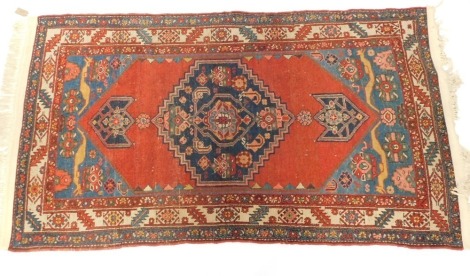 A Turkish red ground rug, decorated with a central floral medallion, further flowers and animals, within repeating leaf and foliate borders, 195cm x 109cm.