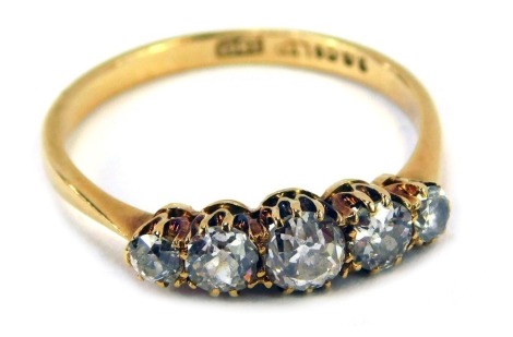 An 18ct gold diamond five stone dress ring, set with five rose cut diamonds, each in claw setting, the largest approximately 0.25ct, flanked by two smaller stones, approximately 0.20ct, and two further stones approximately 0.15ct, in a raised claw setting