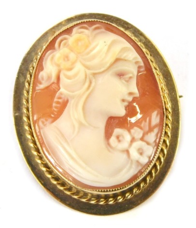 A late 19thC oval shell cameo brooch, depicting maiden with flowers and flowing hair, in a yellow metal brooch casing with single pin back and safety chain, 3cm x 2cm, 6g all in.