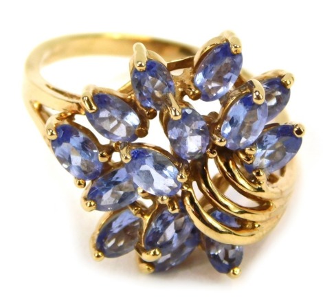 A 9ct gold QVC dress ring, with elaborate left scroll flower spray, set with pale blue/purple tanzanite stones, ring size R½, 5.6g all in.