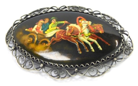 A Russian hand painted brooch, the panel depicting horse and troika, with figures, with white metal filigree scroll border, bearing inscription to reverse, 7cm x 4cm, 12.7g all in.