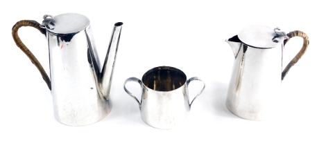 A George V silver three piece coffee service, by Goldsmiths and Silversmiths, comprising coffee pot of plain tapering form, with heart shaped thumb mould and rope handle and plain tapering body, 21cm high, two handled sugar bowl and water jug, London 1923