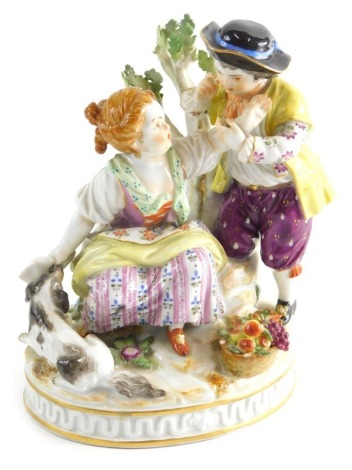 A Meissen porcelain figure group, of children aside dog and basket of fruit, before tree bough, polychrome decorated predominantly in pink, blue, green and orange, with blue cross sword and impressed numbers beneath, 15cm high.