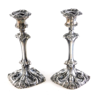 A harlequin pair of William IV candlesticks, by Henry Wilkinson & Co, each repousse decorated with leafy scroll removable sconces, urn finials, inverted stems and leaf and scroll bases, Sheffield 1836 and 1839, 42oz all in. (2, weighted)