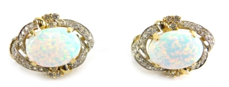 A pair of opal and diamond earrings, each with a central oval opal in claw setting, surrounded by round brilliant cut diamonds, in a yellow and white gold setting, believed to be 18ct but unmarked, 3cm high, 10.8g all in.