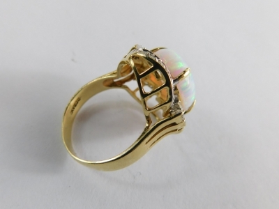 An opal and diamond dress ring, of twist design with central oval opal, in claw setting surrounded by sprays of diamonds, on a raised basket, on a yellow metal band stamped 585, ring size N½ ,6g all in. - 2