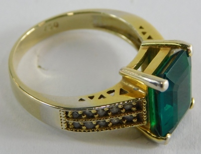 An emerald dress ring, with rectangular cut and faceted emerald, in a four claw setting, measuring 8.8mm x 10.8mm x 4.4mm, totalling approx 3cts, with tiny diamond set shoulders each set with approximately ten diamonds ring size O½ yellow metal stamped 75 - 3