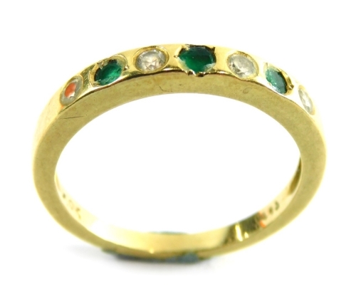 An emerald and diamond half hoop dress ring, set with three emeralds and four diamonds, each in an illusion setting, yellow metal unmarked, ring size O, 2.7g all in.