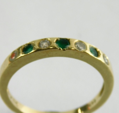 An emerald and diamond half hoop dress ring, set with three emeralds and four diamonds, each in an illusion setting, yellow metal unmarked, ring size O, 2.7g all in. - 2