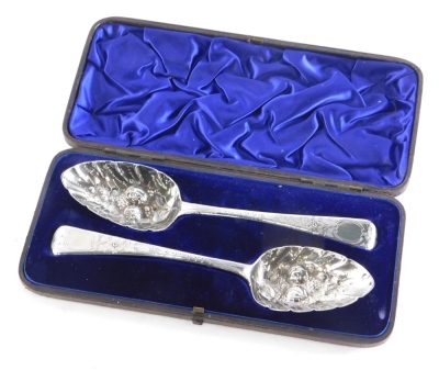 A matched pair of George III silver berry spoons, each repousse decorated and chased with berries and scrolls, with a vacant cartouche, 21cm long, London 1811, etc., 4oz, in an associated case.