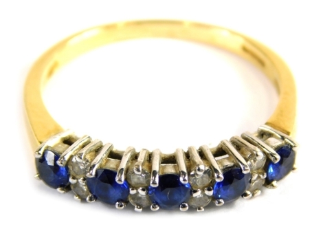 An 18ct gold sapphire and diamond half hoop dress ring, set with five round brilliant cut sapphires, each broken by two round brilliant cut diamonds, in a raised claw platinum setting, on a yellow metal band, ring size R½, 3.4g all in.