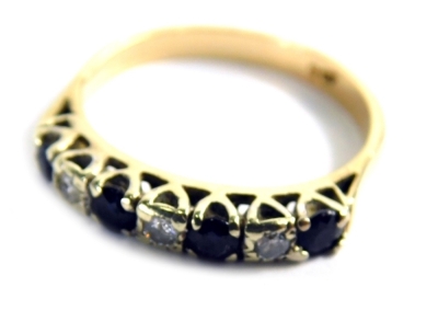 A sapphire and diamond half hoop dress ring, set with four round brilliant cut sapphires and three round brilliant cut diamonds, each in a claw illusion setting, with pierced shoulders, on a yellow metal band marked 9ct, ring size P, 2.9g all in.