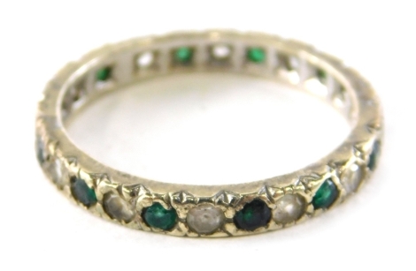 An eternity ring, set with emerald and diamond, white gold set marked 375, ring size M½, 2.3g all in.