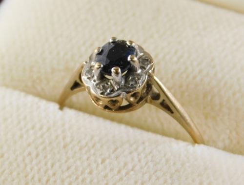 A 9ct gold cluster ring, set with oval sapphire in six claw setting, surrounded by six tiny diamonds, in flared design border with V splayed shoulders, ring size N, 1.5g all in.