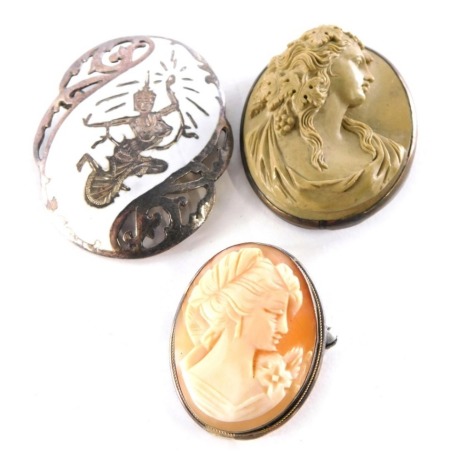 Three costume brooches, comprising a carved lava brooch of a maiden in high relief, in a white metal border, 4.5cm x 3cm, a cameo brooch in white metal setting, unmarked, 2.5cm x 3cm, and an Eastern inspired silver and enamel brooch, depicting female warr