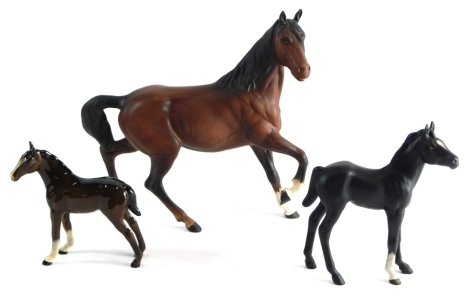 A Beswick matt finish cantering horse, front leg raised, printed marks beneath, 21cm high, a black Beswick foal and a glazed brown foal. (3)