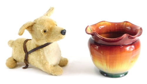 An early 20thC Bretby jardiniere with flared rim splashed decoratively predominately in orange, yellow and green, impressed sun mark beneath, and a Steiff style push jointed Corgi toy (2)