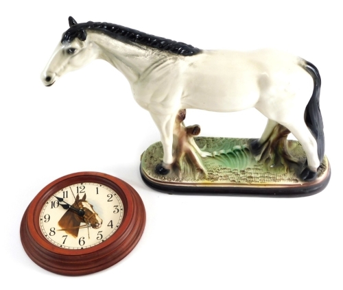 An unusual pottery figure of a standing horse in white, on a naturalistic base, 30cm high and a horse wall clock.