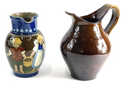 A 20thC Kohler Biel jug, profusely decorated with children, in brown or blue ground, sgrafitto decorated, marked beneath, 21cm high, and a further brown glazed jug, with shaped spout and handle. (2)