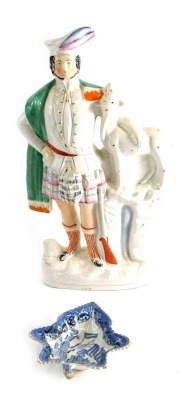 A 19thC Staffordshire flat back figure of a Highlander aside lamb and gun, partially decorated, 41cm high, and a 19thC blue printed pickle dish (2)