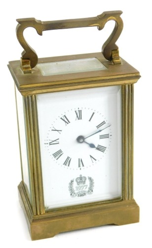 A 20thC Silver Jubilee brass carriage clock, with Royal Crest to the 6cm wide Roman numeric dial, in a five part glazed case, with barrel movement on bracket feet, with swing handle, 14cm high.