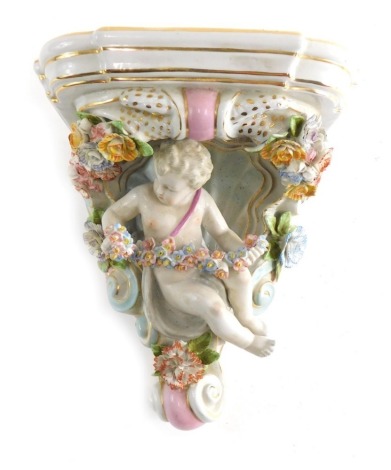 A 20thC Continental porcelain wall shelf, profusely decorated with cherub and garland stem with gild highlighted scroll design and transfer printed floral top blue cross mark 23cms high.