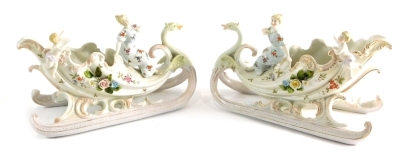 A pair of Continental porcelain figure groups, ladies on sleigh, with cherubs, polychrome decorated and raised with flowers, unmarked, 19cm high.