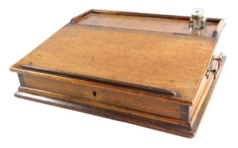 An Edwardian oak table top writing slope, the arched hinged lid revealing a fitted interior with four drawers, with single glass ink well with brass side handles 15cm high 43cm wide 34cm deep.