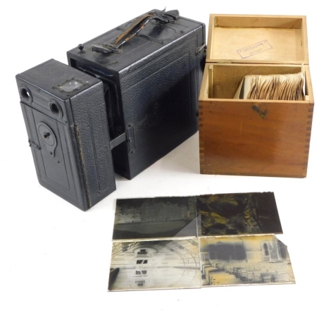 An early 20thC pressed leather box camera, various glass slides country houses, figures etc contained in a dovetailed box.