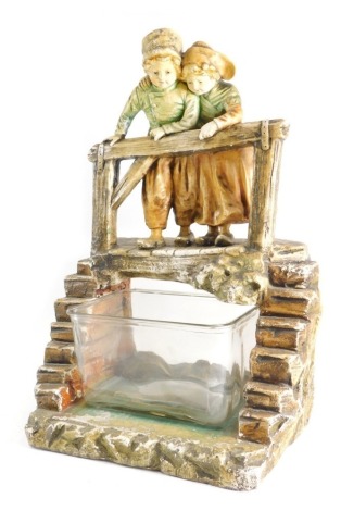 A large 20thC plaster figure group fish tank, formed as children, with steps either side and glass bowl underneath, on a rock work base, 61cm high.