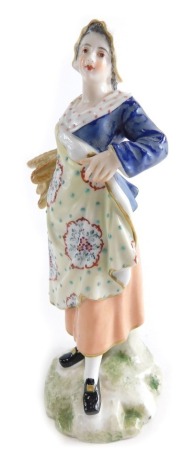 A 19thC Derby porcelain figure of a lady, wearing bonnet and holding wheat, polychrome decorated red crown mark beneath, 19cm high.
