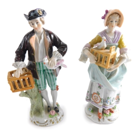 A pair of 20thC Sitzendorf porcelain figures, of a lady, dressed in finery holding bird and box, and a gentleman similar, with gilt highlights, each marked beneath, 15cm high.