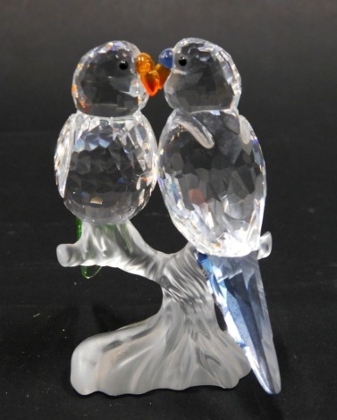 A Swarovski Crystal figure group of lovebirds, in clear, frosted, orange, blue and black glass, swan mark beneath, 9cm high.