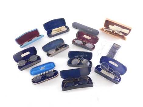 Various optical items and spectacles, a pair of metal rimmed spectacles in oval case, with curved side bars, 13cm wide, a tin spectacle case containing further spectacles, etc. (a quantity)