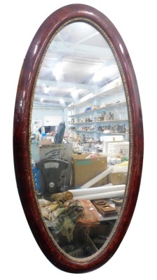 A large oval hanging mirror, in simulated frame, with giltwood moulding, plain glass, 127cm x 63cm.