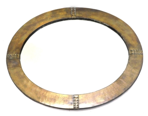 A 20thC hammered copper Arts and Crafts style mirror, of oval form, the plain border broken by studded sections, 65cm x 51cm.