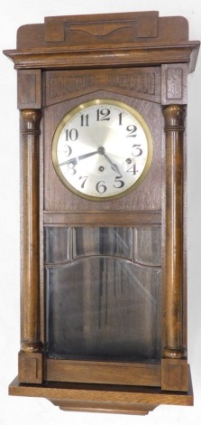 A 20thC oak cased wall clock, with 18cm diameter Arabic dial, fronted by a glazed panel door, in shaped case with pendulum and key, 72cm high.