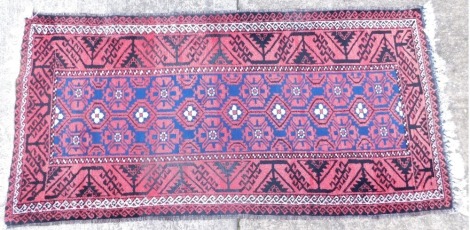 A 20thC middle eastern carpet runner, of rectangular form the outer field in a floral geometric pattern in black and red with inner decoration in cream blue and red 213cm x 102cm.