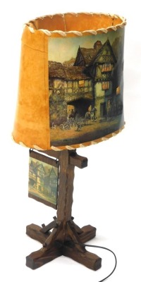 An oak table lamp, with leather shade transfer printed with tavern scene marked Bennet, on a carved stem and X shaped feet, 88cm high.