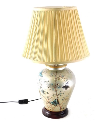 An urn table lamp, the semi porcelain urn body decorated with butterflies and flowers on a silver ground on circular foot with modern shade 65cm high.