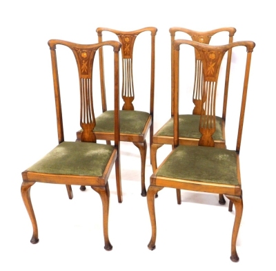 A set of four Edwardian mahogany and boxwood strung Sheraton revival dining chairs, with comb top rails, inverted pierced splats, inset with mother of pearl hearts and flowers, above drop in seats in green material, on cabriole front and sabre back legs,