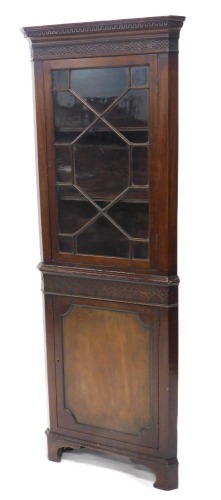 A mahogany freestanding corner cabinet, the dentil top with a blind fret, above an astragal glazed door and single cupboard, on bracket feet, 183cm high, 66cm wide, 50cm deep.