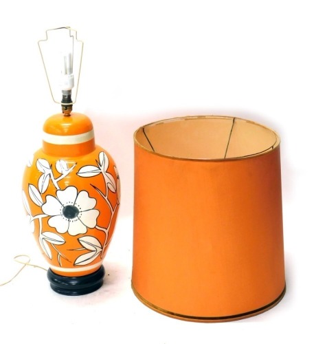 An orange retro pottery table lamp, with fixed top, vibrantly decorated with flowers, on a white and black ground, 80cm high. Buyer Note: WARNING! This lot contains untested or unsafe electrical items. It is supplied for scrap or reconditioning only. TRAD