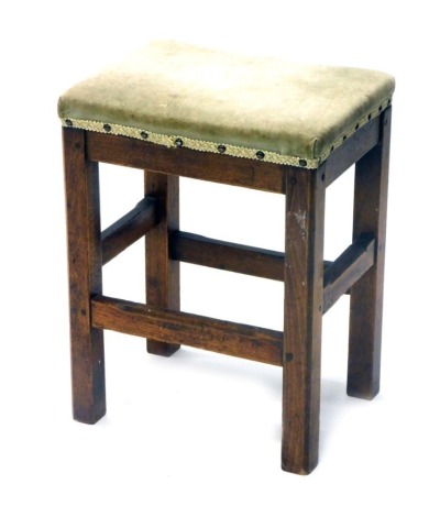 An early 20thC oak stool, overstuffed in later green material, on chamfered legs with block stretchers, 46cm high, 36cm wide, 27cm deep.