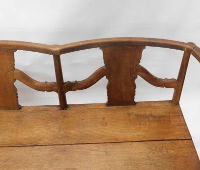 An oak Arts and Crafts style settle, with serpentine back, on turned supports with a carved frieze, on cylindrical stiles, 76cm high, 183cm wide, 51cm deep. - 2