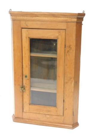 A pine hanging corner cabinet, the glazed door revealing two shelves, on a moulded base, 118cm high, 78cm wide, 49cm deep.