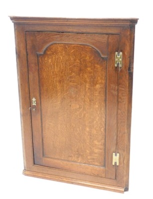 An 18thC oak hanging corner cupboard, with panelled door revealing three shelves, 105cm high, 74cm wide, 37cm deep.