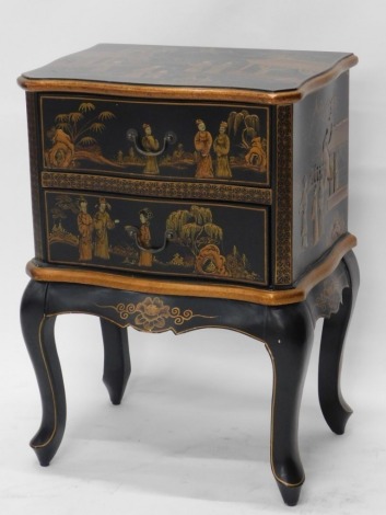 A Japanned lacquer finish side cabinet, with serpentine top, two drawers and cabriole legs, profusely decorated with figures, buildings, trees, and mountains, 68cm high, 49cm wide, 23cm deep.