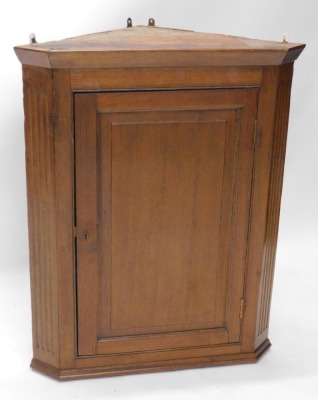 An oak hanging corner cupboard, with panelled door revealing shelves, in carved case, 88cm high, 70cm wide, 50cm deep.